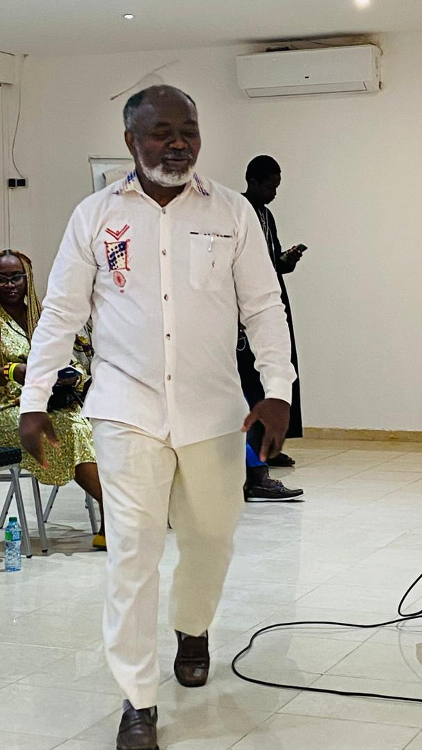 Dr. Gnaka Lagoke wearing a white embroidered shirt at an indoor gathering